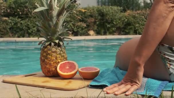 パイナップルとグレープフルーツのプールラドムトレイの端にいる女の子 — ストック動画