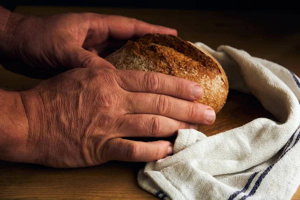 black round bread in the hands of a man in the style of rustic