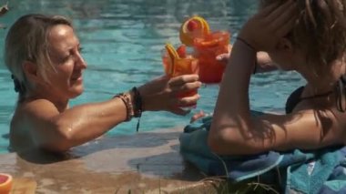 Yüzme havuzunda elinde kokteyllerle bikinili iki güzel kız.