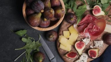 Masanın üstünde tahta tahta üzerinde marul ve incirle doğranmış peynir.