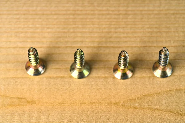 The screws turned up by the sharp part lie on the wooden surface of the closeup. — Stock Photo, Image