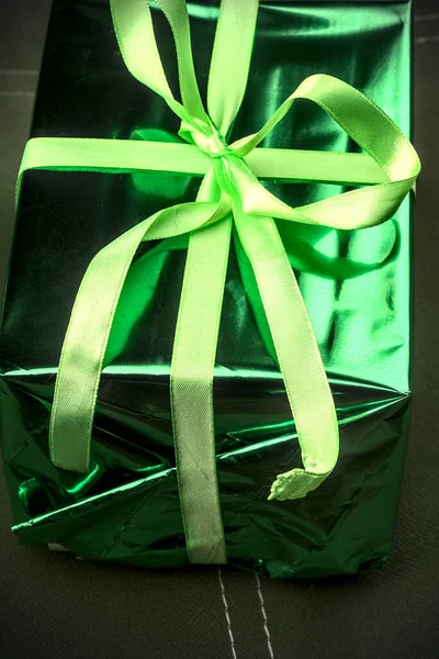 Una hermosa caja de regalo de color verde atada con una cinta. Luces atenuadas. —  Fotos de Stock