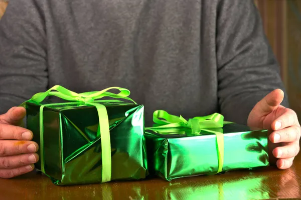 Dois presentes de aniversário verdes em suas mãos na mesa — Fotografia de Stock
