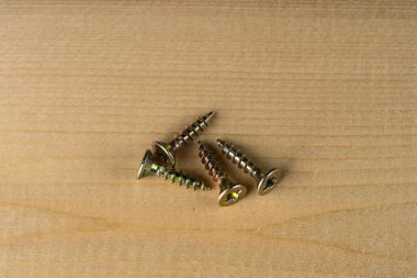 Vidalar ahşap bir yüzey üzerinde yakın çekim yığını içinde yatıyor.