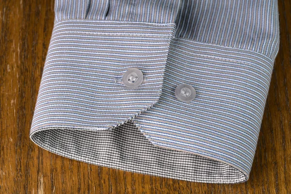 MOSCOW, RUSSIA-October 22, 2021: The sleeve of a gray office shirt with buttons on a wooden background closeup — Stock Photo, Image