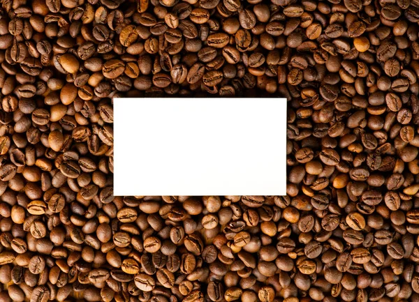 Una consistenza di chicchi di caffè tostati con una carta bianca al centro per il testo. — Foto Stock
