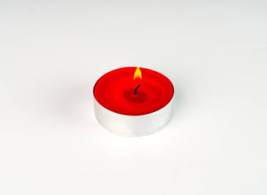 Yanan küçük kırmızı bir mum beyaz bir arkaplanda yakındır.