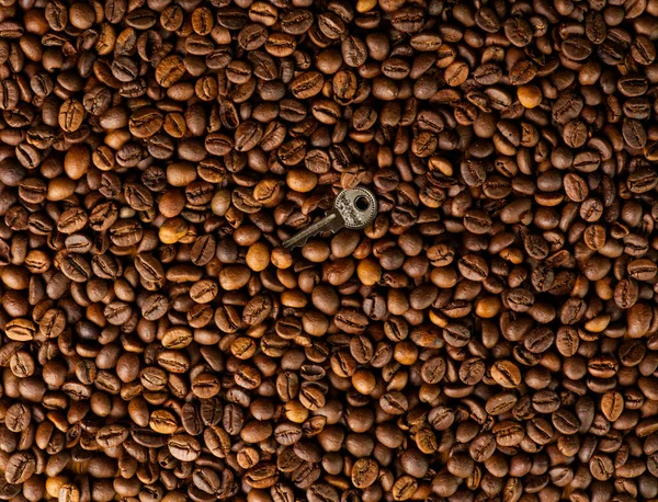 The concept of getting out of a difficult situation through thoughtful actions. The texture of the coffee beans and the key in the middle as a symbol — Stock Photo, Image