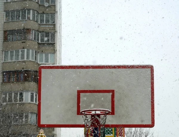 Aro de baloncesto con un escudo cerrado para streetball en invierno. La nieve cae — Foto de Stock