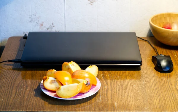 MOSCÚ, RUSIA-22 de noviembre de 2021: Trabajo desde casa de forma remota. Hay un portátil cerrado y un plato de fruta en la mesa. Junto al ratón de ordenador Lifestyle —  Fotos de Stock