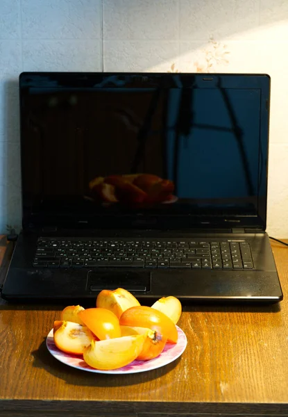 MOSCÚ, RUSIA-22 de noviembre de 2021: Trabajo desde casa de forma remota. Durante el período de autoaislamiento de la pandemia. Hay una computadora portátil y un plato de fruta en la mesa. Estilo de vida — Foto de Stock