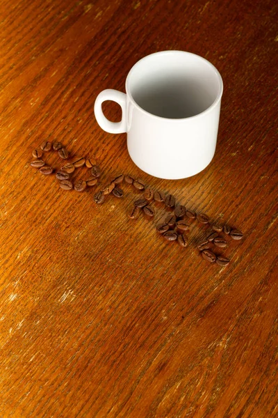 Lettering chicco di caffè e una tazza bianca su uno sfondo di legno. — Foto Stock