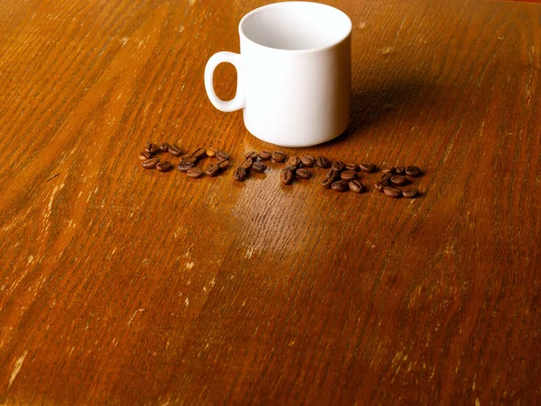 Una tazza bianca su uno sfondo di legno e l'iscrizione caffè. — Foto Stock