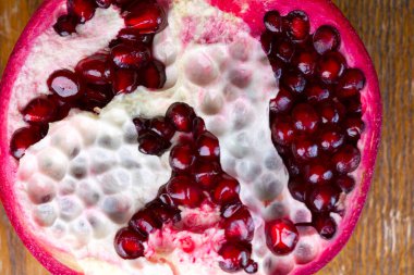 Parlak kırmızı taneli kocaman bir nar meyvesinin yarısı yakın plan.