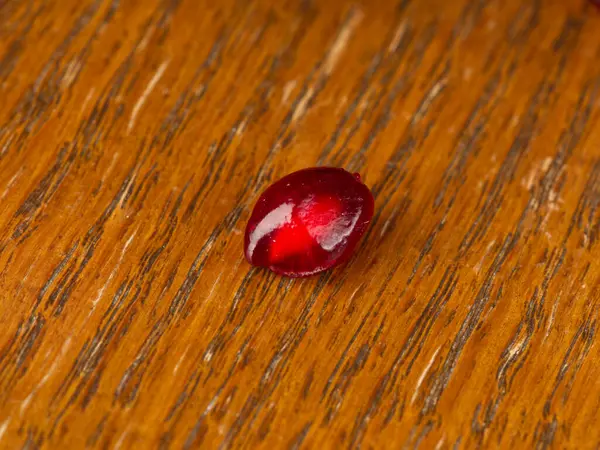 Un granello di melograno rosso brillante su uno sfondo di legno. — Foto Stock