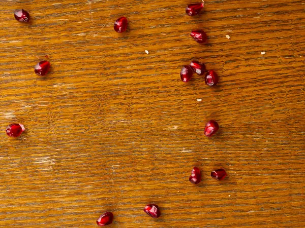 Grani di frutta melograno rosso brillante su uno sfondo di legno — Foto Stock