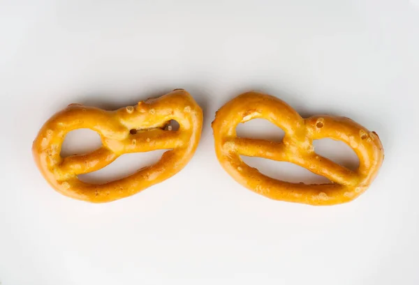 Dua wajah dalam bentuk pretzel. Satu pretzel mengedipkan mata dan yang lainnya tersenyum. Pada latar belakang putih. — Stok Foto