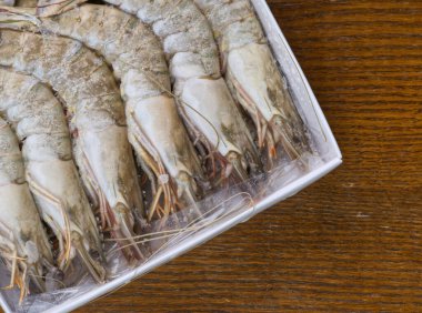 Ahşap bir arka planda pakette kocaman donmuş karides. Üst görünüm