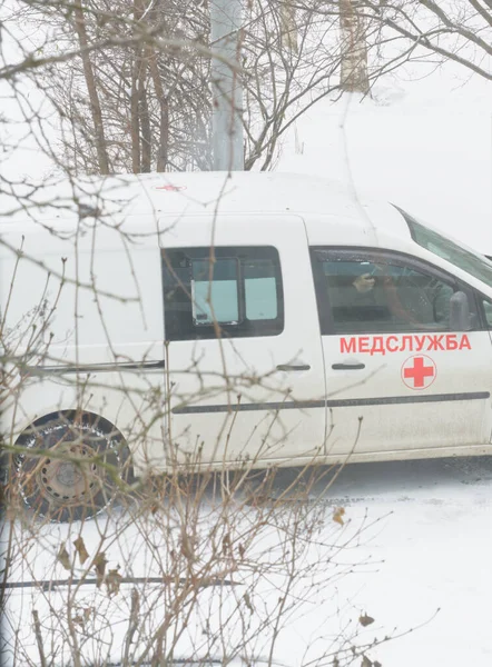 MOSKAU, RUSSLAND - 11. Dezember 2021: Ein Krankenwagen ist angerückt und steht in der Nähe des Hauses. Blick aus dem Fenster. Es schneit überall — Stockfoto