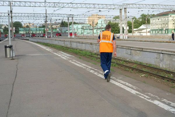 MOSCOW, RUSSIA-10 sierpnia 2021: Kazański dworzec kolejowy w Moskwie latem. Pracownik stacji idzie po peronie w pomarańczowej kamizelce. — Zdjęcie stockowe