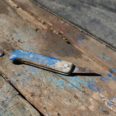 Eski, paslı bir ev yapımı bıçak ahşap bir masada yatıyor..