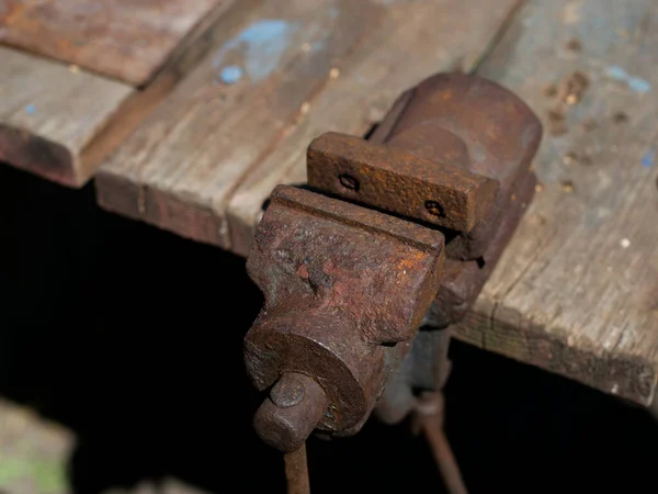 Aan de tafel is een oude roestige metalen bankschroef bevestigd — Stockfoto