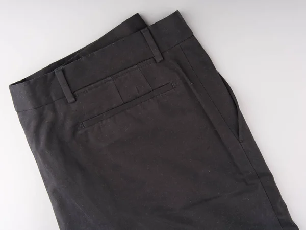 Oude zwarte broek dubbel gevouwen op een lichtgrijze achtergrond. Bovenaanzicht — Stockfoto