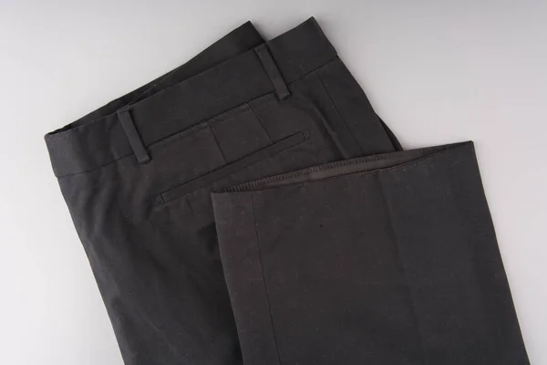 Pantalón negro doblado por la mitad. Tanto el cinturón como las patas del pantalón son visibles. Sobre un fondo gris. —  Fotos de Stock