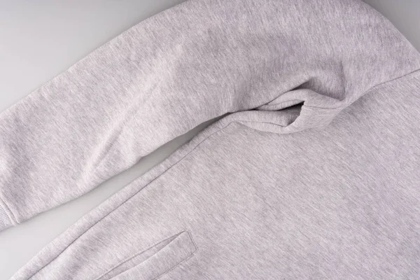 Onderdeel van een lichtgrijze sweater op een grijze achtergrond. De mouw en zak zijn zichtbaar. Bovenaanzicht — Stockfoto
