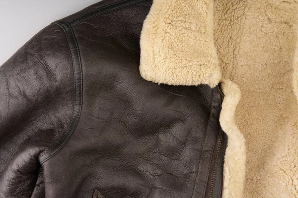 Część ciepłej męskiej kurtki ze skóry i naturalnego owczego futra na szarym tle. Ciepłe zimowe ubrania. Blisko. — Zdjęcie stockowe
