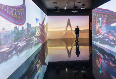 Duvardaki projeksiyonları inceleyen bir adamın fotoğrafı.