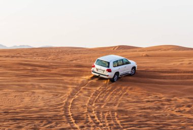 Bir SUV aracının kum tepelerinden geçerken görüntüsü.