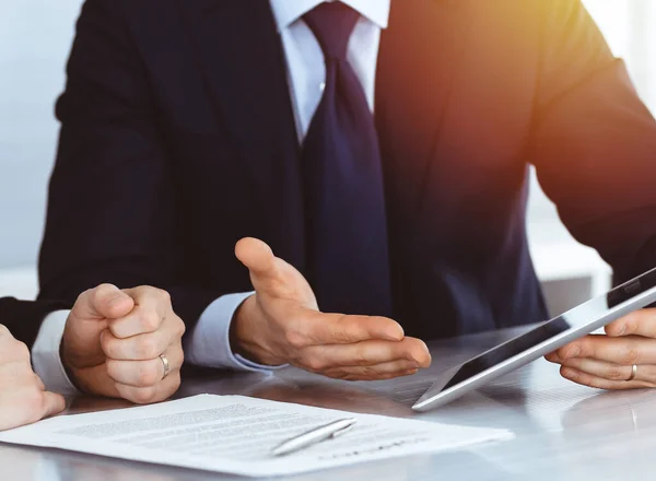 Gente de negocios que usa tableta mientras trabajan juntos en la soleada oficina moderna. Hombre de negocios desconocido con colega en el lugar de trabajo. Trabajo en equipo y concepto de asociación — Foto de Stock