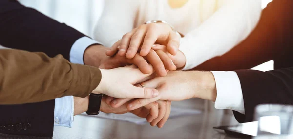 Podnikatelé ukazují týmovou práci a drží se za ruce nebo dávají pět v slunné kanceláři. Neznámý podnikatel a ženy krouží rukama. — Stock fotografie