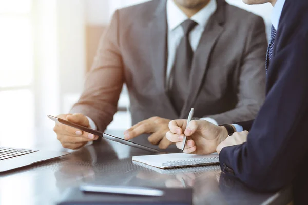 Hombre de negocios desconocido que utiliza la computadora de la tableta y el trabajo junto con su colega mientras se sienta en el escritorio de cristal en la oficina moderna. Trabajo en equipo y concepto de asociación — Foto de Stock