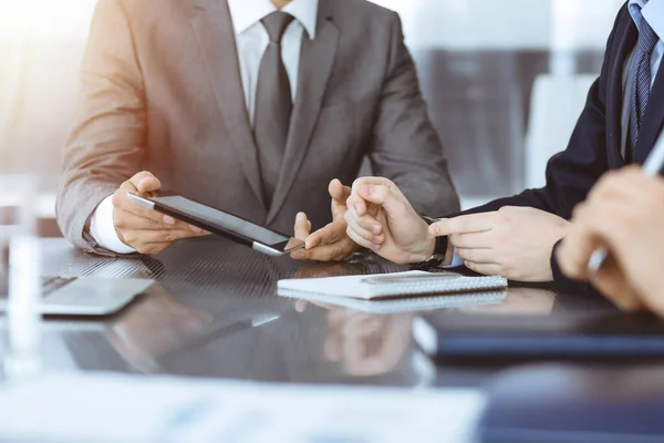 Hombre de negocios desconocido que utiliza la computadora de la tableta y el trabajo junto con su colega mientras se sienta en el escritorio de cristal en la oficina moderna. Trabajo en equipo y concepto de asociación — Foto de Stock