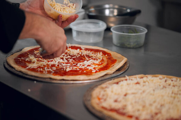 Close up of chef hands making a pizza laying cheese