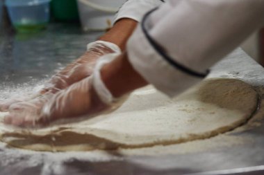 Close up of chef spreading dough for pizza