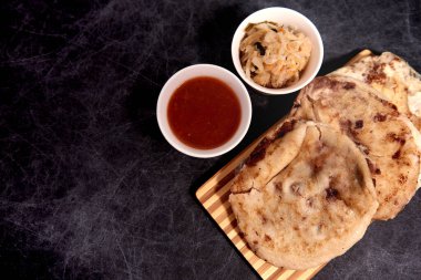 Ahşap bir tahtanın üzerinde siyah mermer bir arka planda el yazısı ve sos olan köpek yavruları.