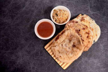 Ahşap bir tahtanın üzerinde siyah mermer bir arka planda el yazısı ve sos olan köpek yavruları.