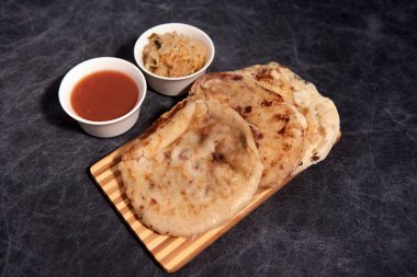 Ahşap bir tahtanın üzerinde siyah mermer bir arka planda el yazısı ve sos olan köpek yavruları.