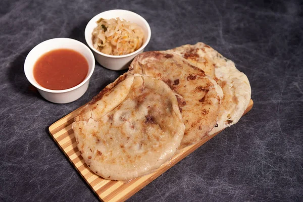 Ahşap bir tahtanın üzerinde siyah mermer bir arka planda el yazısı ve sos olan köpek yavruları.