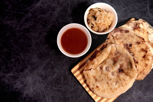 Ahşap bir tahtanın üzerinde siyah mermer bir arka planda el yazısı ve sos olan köpek yavruları.