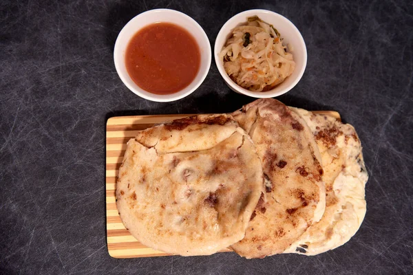 Ahşap bir tahtanın üzerinde siyah mermer bir arka planda el yazısı ve sos olan köpek yavruları.