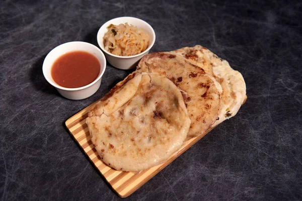 Ahşap bir tahtanın üzerinde siyah mermer bir arka planda el yazısı ve sos olan köpek yavruları.