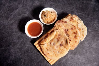 Ahşap bir tahtanın üzerinde siyah mermer bir arka planda el yazısı ve sos olan köpek yavruları.