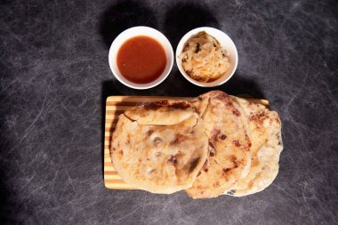 Ahşap bir tahtanın üzerinde siyah mermer bir arka planda el yazısı ve sos olan köpek yavruları.