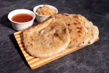 Ahşap bir tahtanın üzerinde siyah mermer bir arka planda el yazısı ve sos olan köpek yavruları.