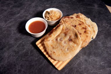 Ahşap bir tahtanın üzerinde siyah mermer bir arka planda el yazısı ve sos olan köpek yavruları.