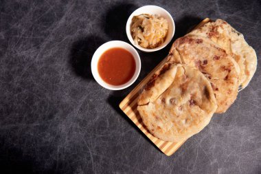 Ahşap bir tahtanın üzerinde siyah mermer bir arka planda el yazısı ve sos olan köpek yavruları.